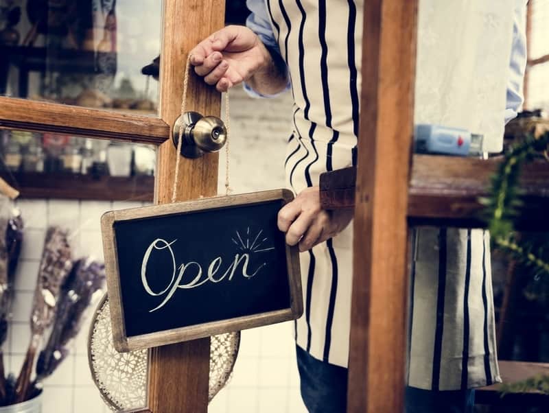 store owner placing an open sign on entrance door