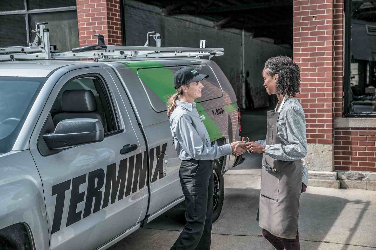terminix technician in front of truck talking to woman