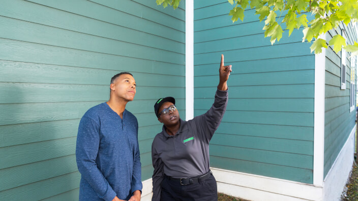 Terminix tech pointing at a tree with a customer