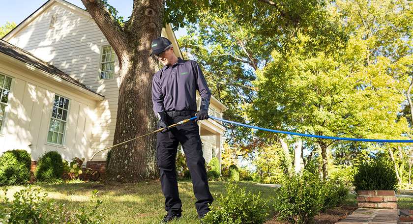pest control partner with hose in front of house
