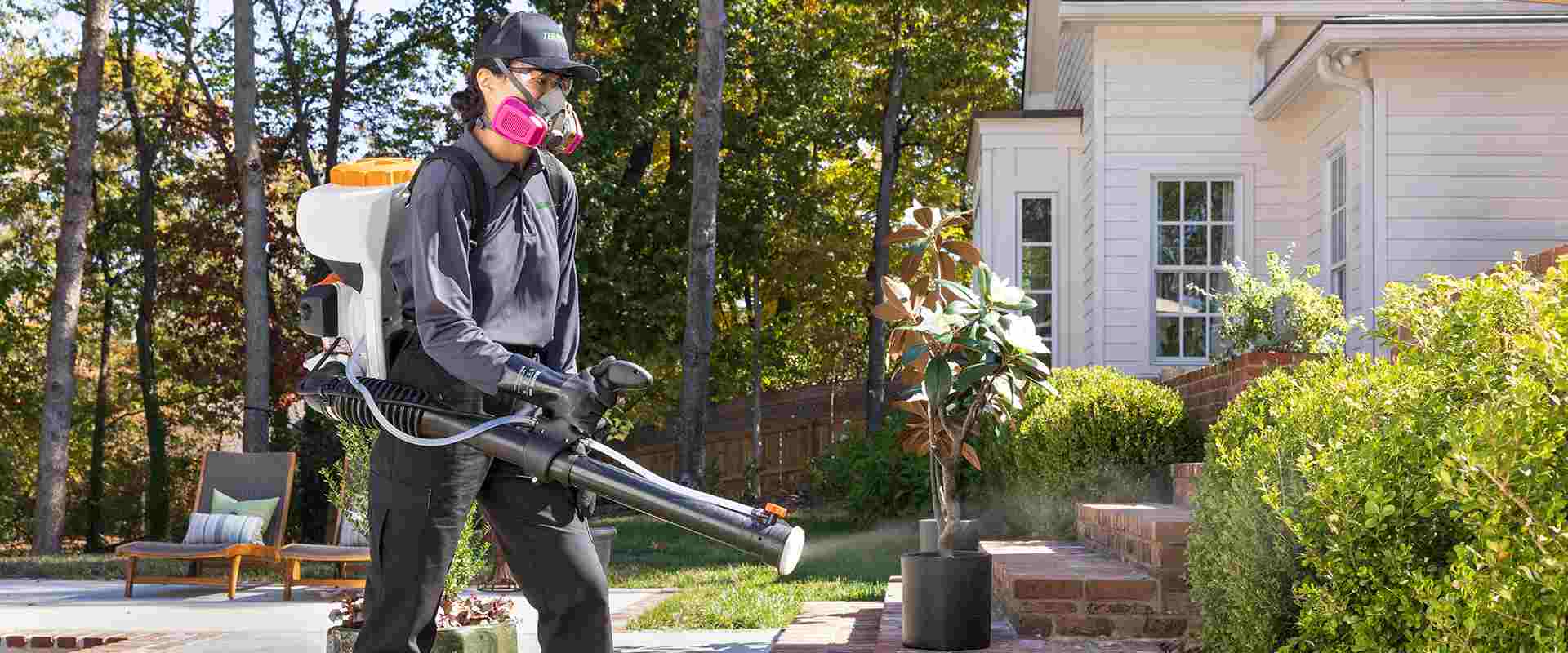 Technician in protective gear spraying for mosquitos
