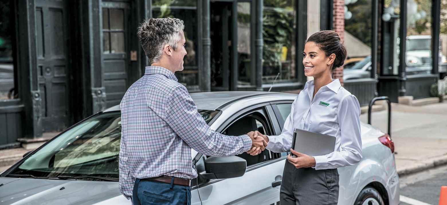 man shaking terminix employee hand near car