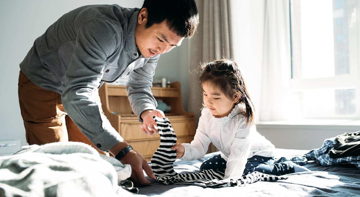 A father helping his daughter lay out her clothes