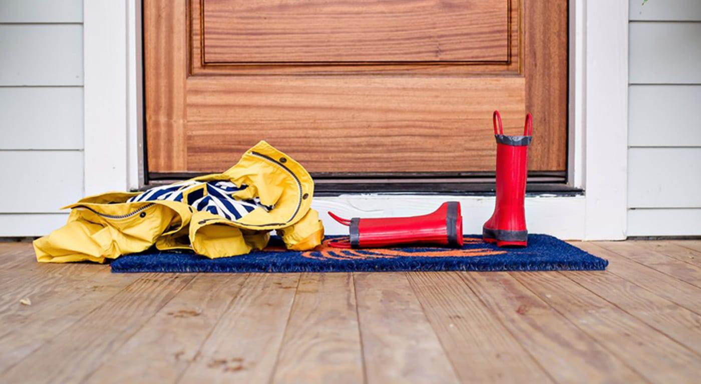 A front porch with child's raincoat and boots lying in front of door