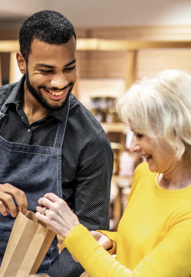 Store worker handing a paper bag to an elderly woman